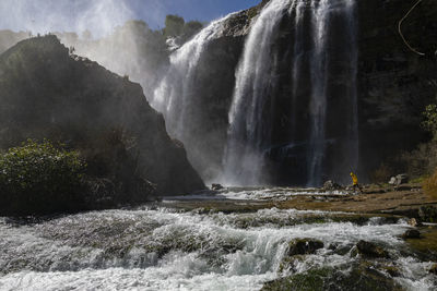 Man standing against waterfall