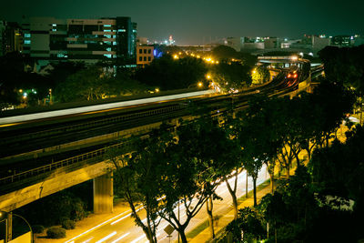 Illuminated road by city against sky at night