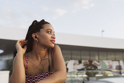 Young woman listening to music through in-ear headphones