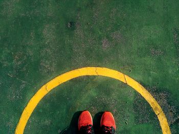 Low section of person standing by yellow shoes