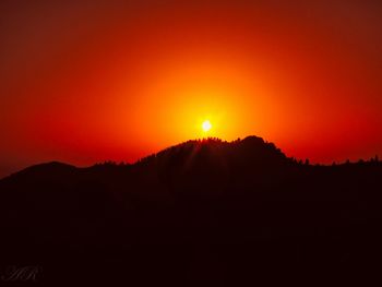 Scenic view of silhouette mountains against orange sky