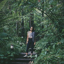 Portrait of woman standing amidst trees in forest