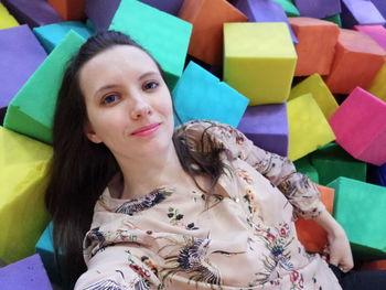 High angle portrait of smiling young woman lying on colorful blocks