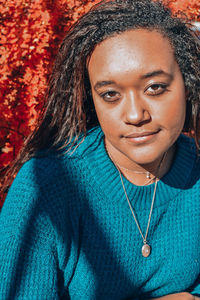 Portrait of beautiful young woman standing against red plants