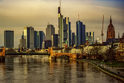 River by modern buildings against sky in city