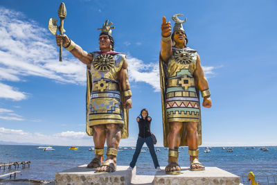 Woman posing at statues of sun god and moon goddess, lake titicaca