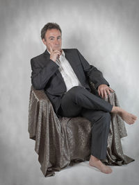 Portrait of a man sitting against gray background