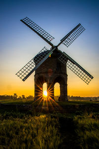 Traditional windmill on field against sky at sunset