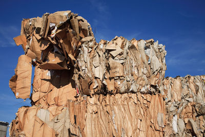 Low angle view of stacked papers at junkyard against sky