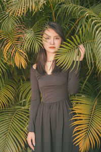 Portrait of young woman standing against plants