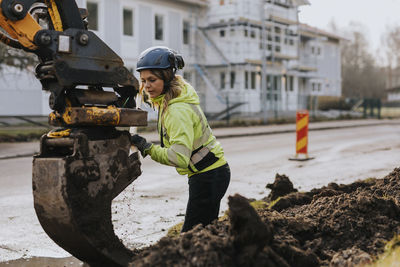 Female road worker and excavator at digging site