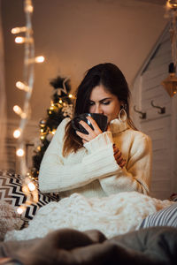 Young woman sitting with umbrella at home