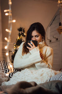 Woman drinking coffee in illuminated room