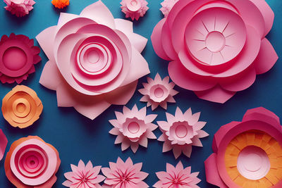 Pink paper cut flowers on blue background. abstract floral pattern