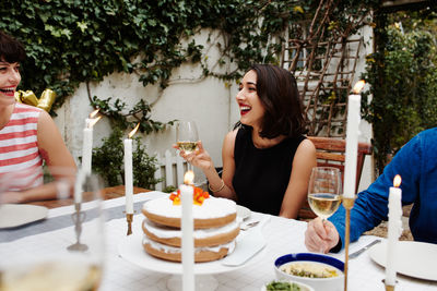 Happy woman holding wineglass while sitting at table