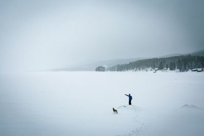 High angle view of person with dog on snow covered field against sky