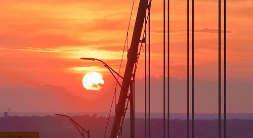 Silhouette bridge against orange sky during sunset