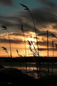 Scenic view of lake against dramatic sky during sunset