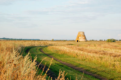 An old brick building stands alone in a field. an old dilapidated mill against the backdrop 