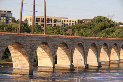 Arch bridge in city against sky