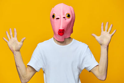 Rear view of woman wearing mask against yellow background