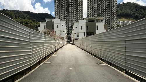 Walkway amidst trees in city against sky