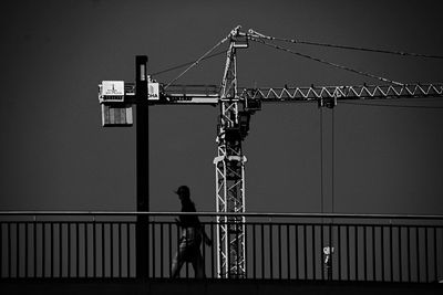 Low angle view of silhouette crane against clear sky