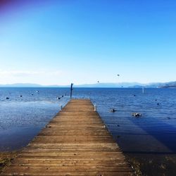 Pier over sea against clear blue sky