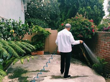 Rear view of man watering plants in yard