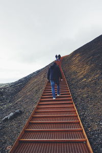 People walking on steps against clear sky at volcanic crater