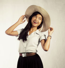 Portrait of smiling young woman standing against gray background