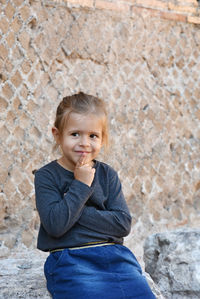 Cute girl sitting against wall