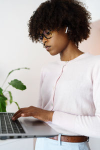 Black woman with afro hair with ear buds earphones holding laptop during video conference