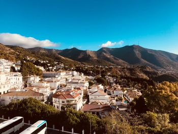 High angle view of townscape and mountains against blue sky