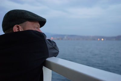 Close-up of man at railing by sea against sky