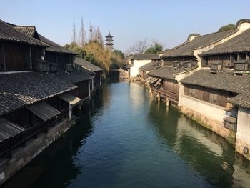 View of buildings by river against sky