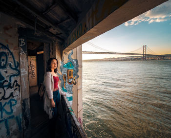 Woman standing at abandoned building by sea