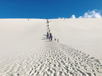 People walking on sand against sky