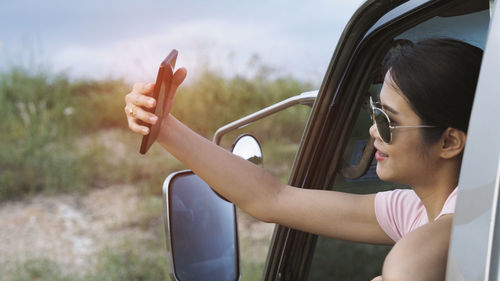 Midsection of woman wearing sunglasses while sitting on field