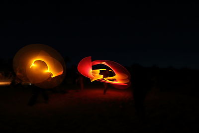 Illuminated orange lights against sky at night