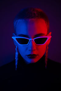 Portrait of woman wearing sunglasses against black background