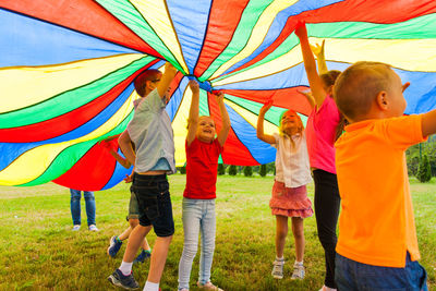 Full length of kids playing with multi colored textile at park