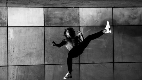 Low angle view of woman jumping against wall