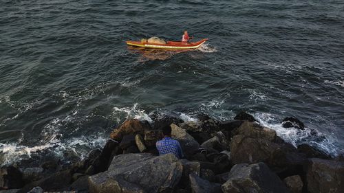 High angle view of people on rock in sea