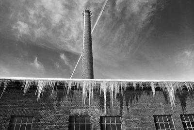 Low angle view of icicles on industry building against sky