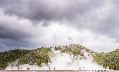 Panoramic view of people on landscape against cloudy sky