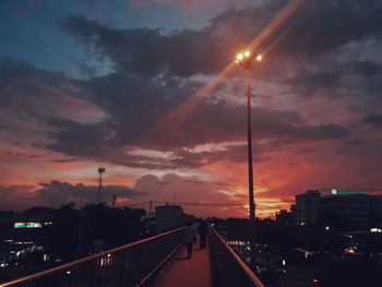 Cars on street against sky at sunset