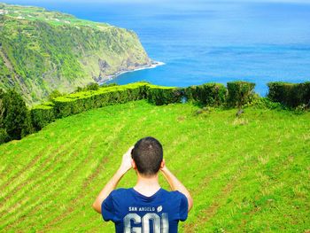 Rear view of man on field against sea