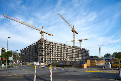 Cranes at construction site against sky in city