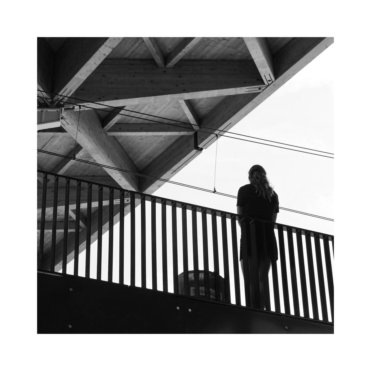 REAR VIEW OF MAN STANDING BY RAILING